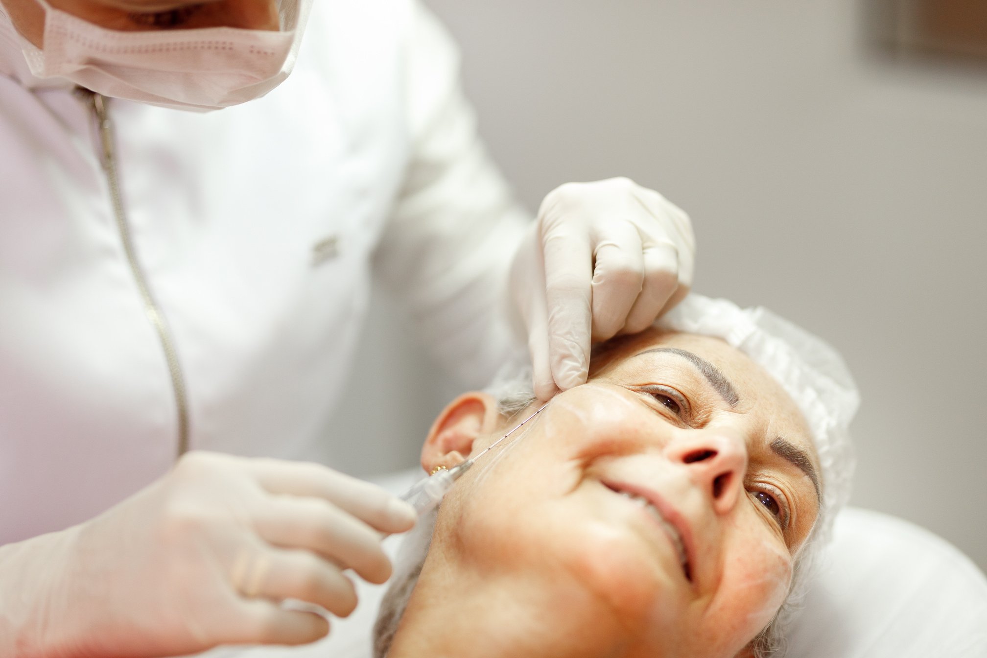 Woman smiling to help beautician apply biostimulants on her face